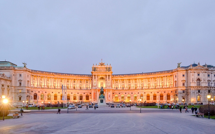 New Hofburg Palace exterior in Vienna, Austria, illuminated at dusk.