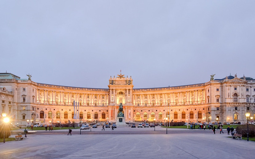 New Hofburg Palace exterior in Vienna, Austria, illuminated at dusk.