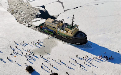 Icebreaker Arktis navigating frozen sea with tourists walking on ice, Kemi.