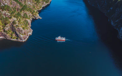 Cruise boat navigating Mostraumen Fjord near Bergen, surrounded by steep cliffs.
