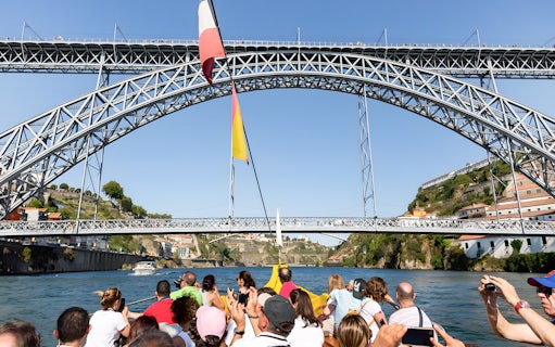 Passengers on Douro River cruise viewing Porto's iconic bridges.