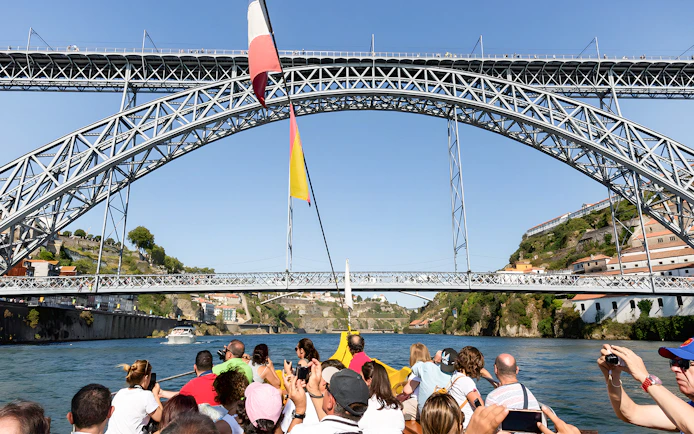 Passengers on Douro River cruise viewing Porto's iconic bridges.