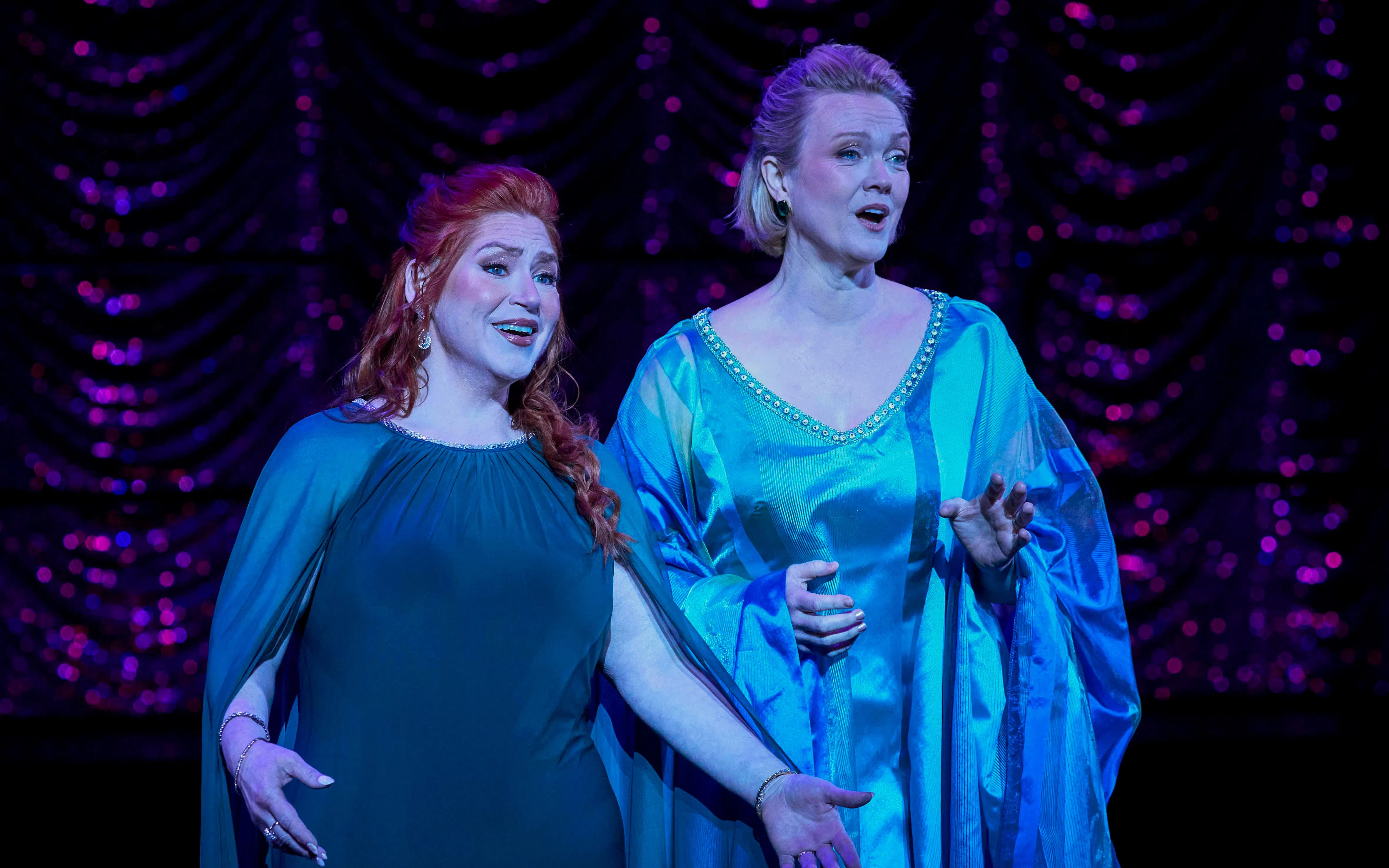 Two performers singing on stage in a scene from My Fair Lady.