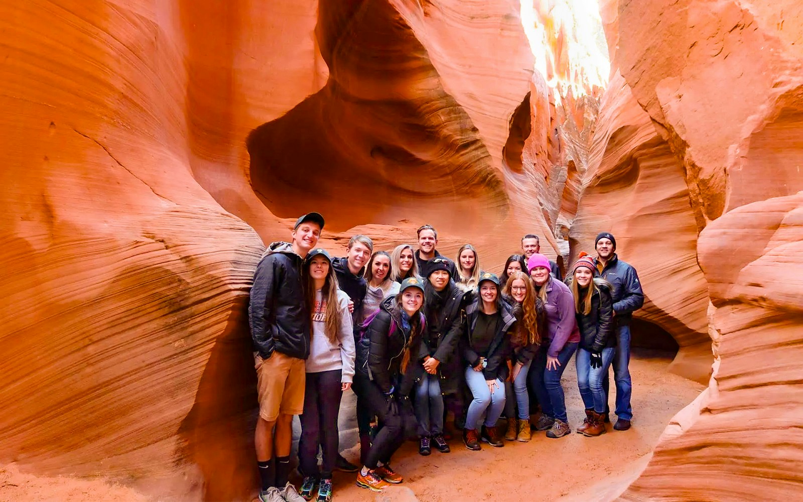Group of tourists exploring Secret Antelope Canyon's sandstone formations.