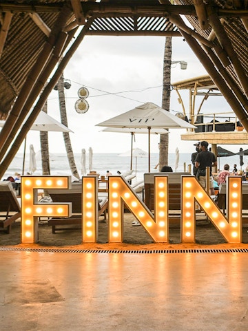 Finns Beach Club entrance with illuminated sign, Bali beachfront view.