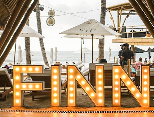Finns Beach Club entrance with illuminated sign, Bali beachfront view.