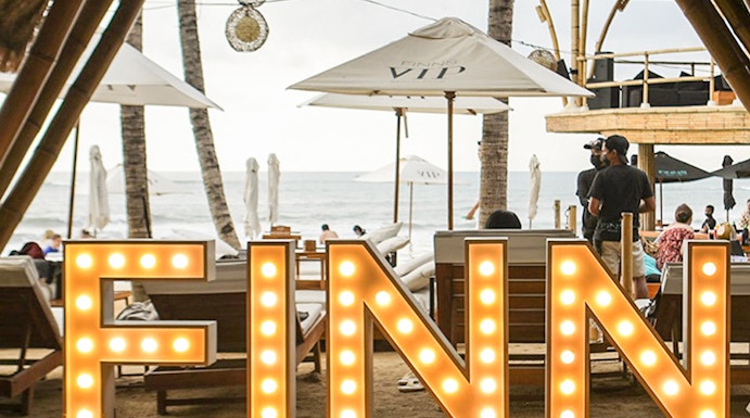 Finns Beach Club entrance with illuminated sign, Bali beachfront view.