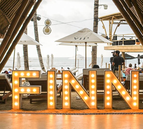 Finns Beach Club entrance with illuminated sign, Bali beachfront view.