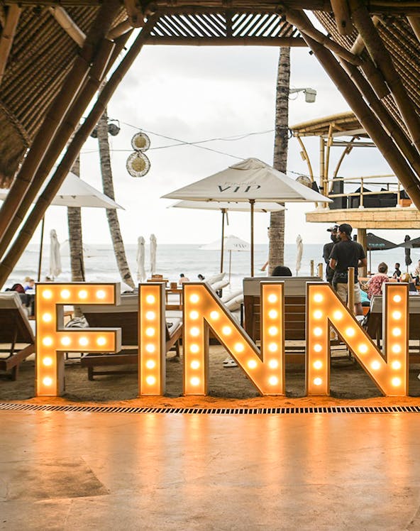 Finns Beach Club entrance with illuminated sign, Bali beachfront view.