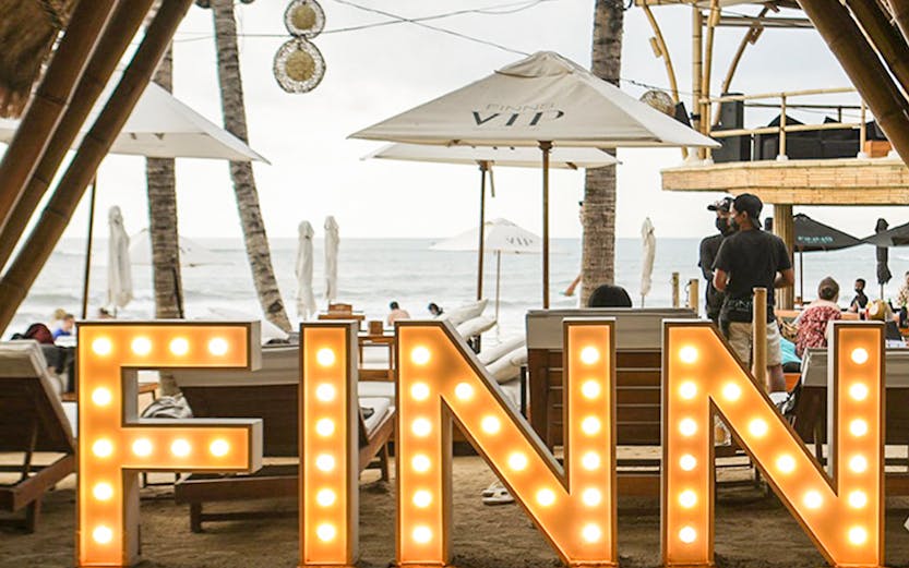 Finns Beach Club entrance with illuminated sign, Bali beachfront view.