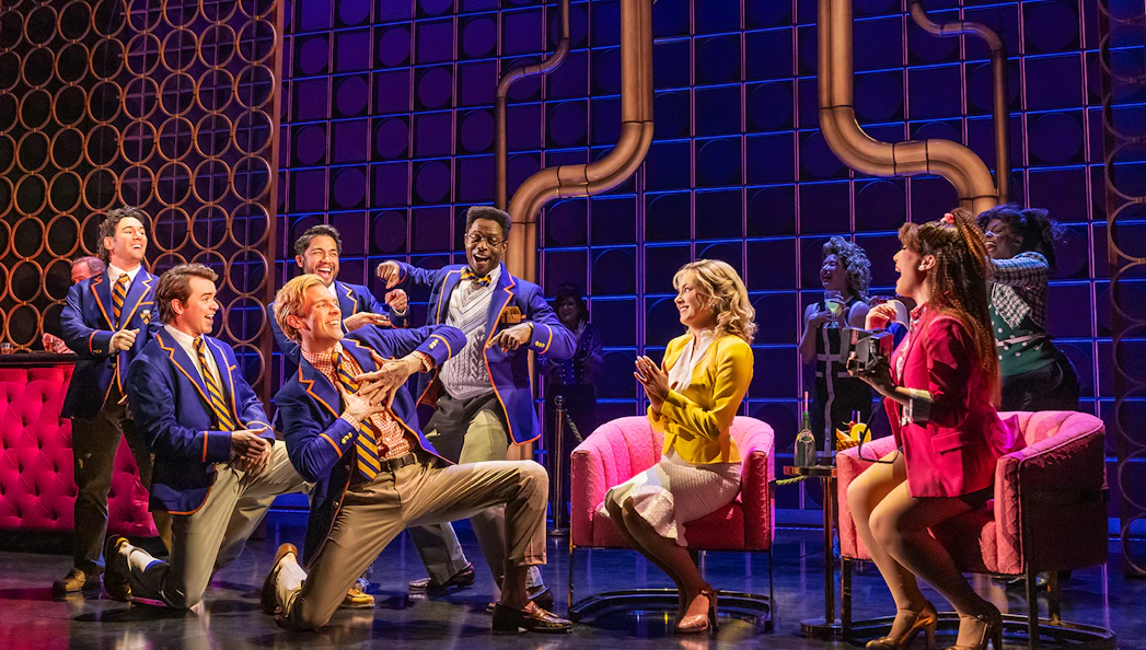 Musical cast performing lively scene in "The Heart of Rock and Roll" show.