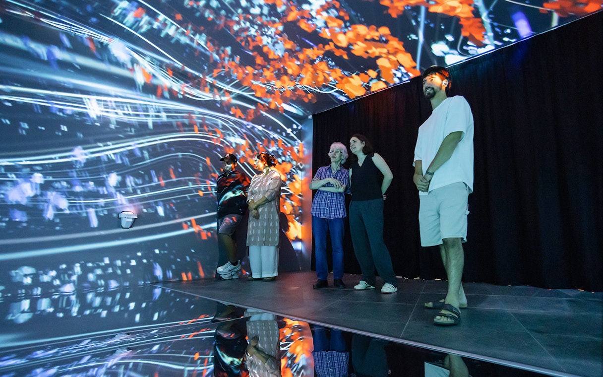 Visitors at Espai Crater viewing digital display with vibrant abstract visuals.