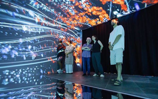 Visitors at Espai Crater viewing digital display with vibrant abstract visuals.