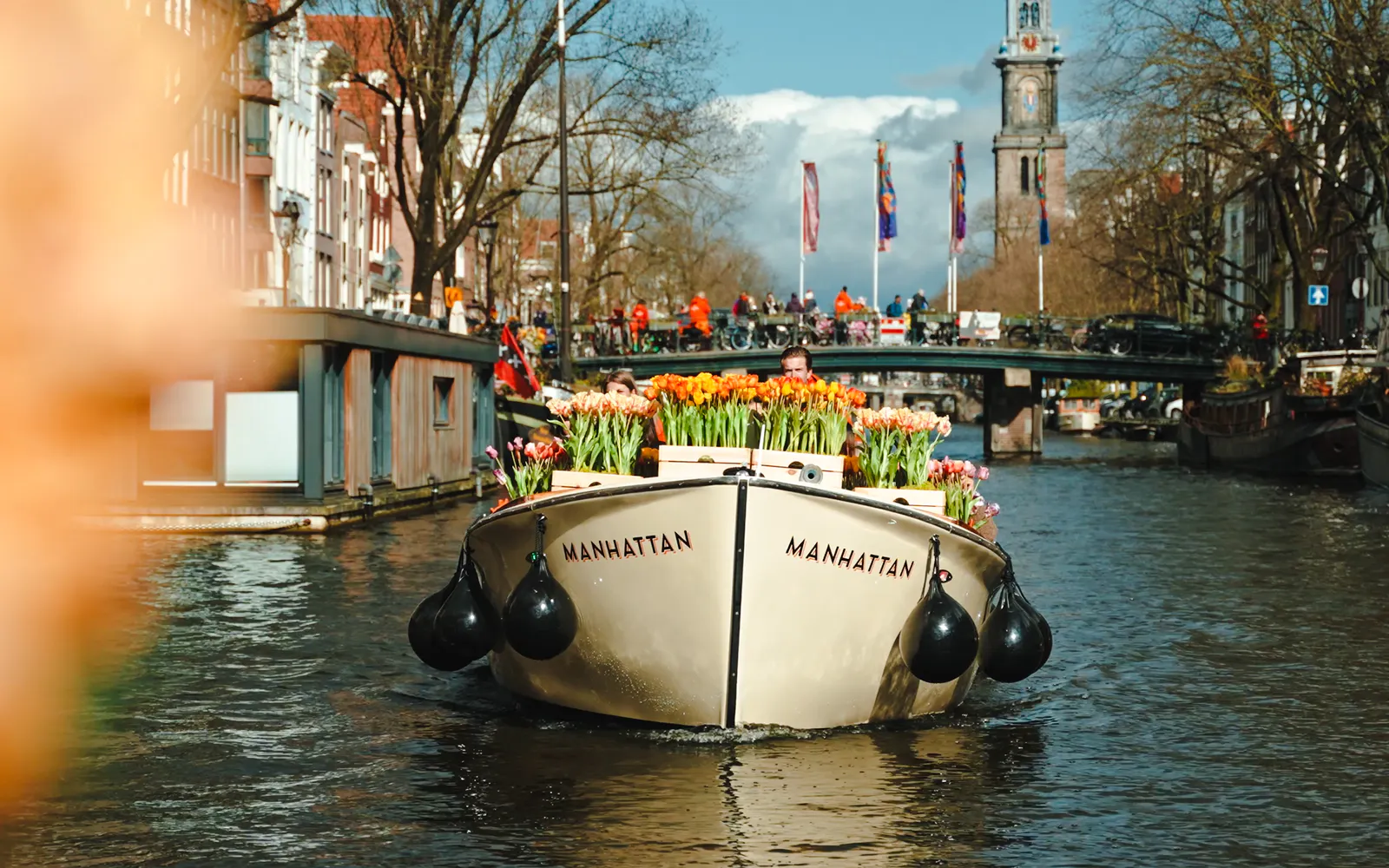 Luxury cruise boat with tulips on Amsterdam canal, Westerkerk in background.