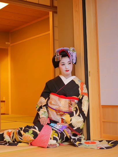 Geisha in traditional kimono posing in a Japanese tea house.