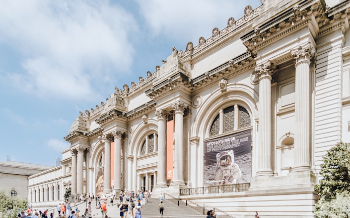 Metropolitan Museum of Art exterior with columns and visitors on steps, New York City.