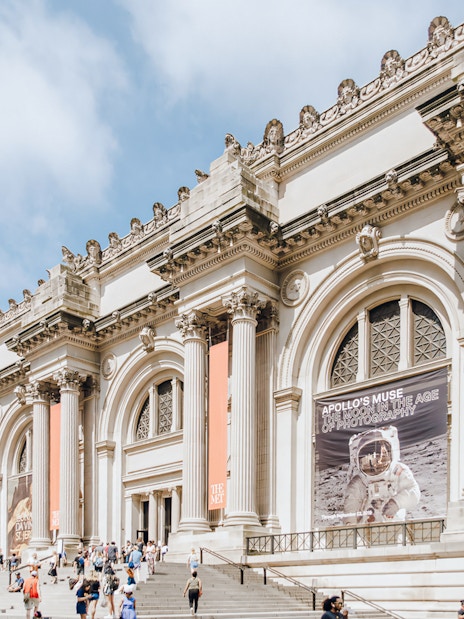 Metropolitan Museum of Art exterior with columns and visitors on steps, New York City.