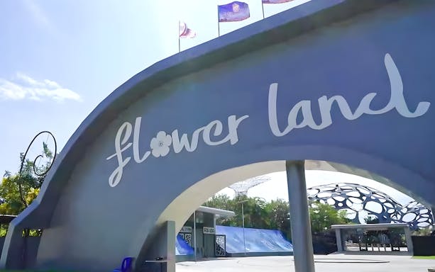 Entrance archway of Flower Land Pattaya with decorative structures in the background.