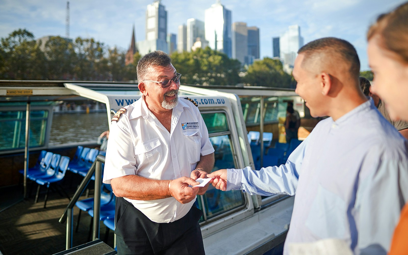 Cruise captain checking tickets of guests on Yarra River sightseeing cruise in Melbourne.