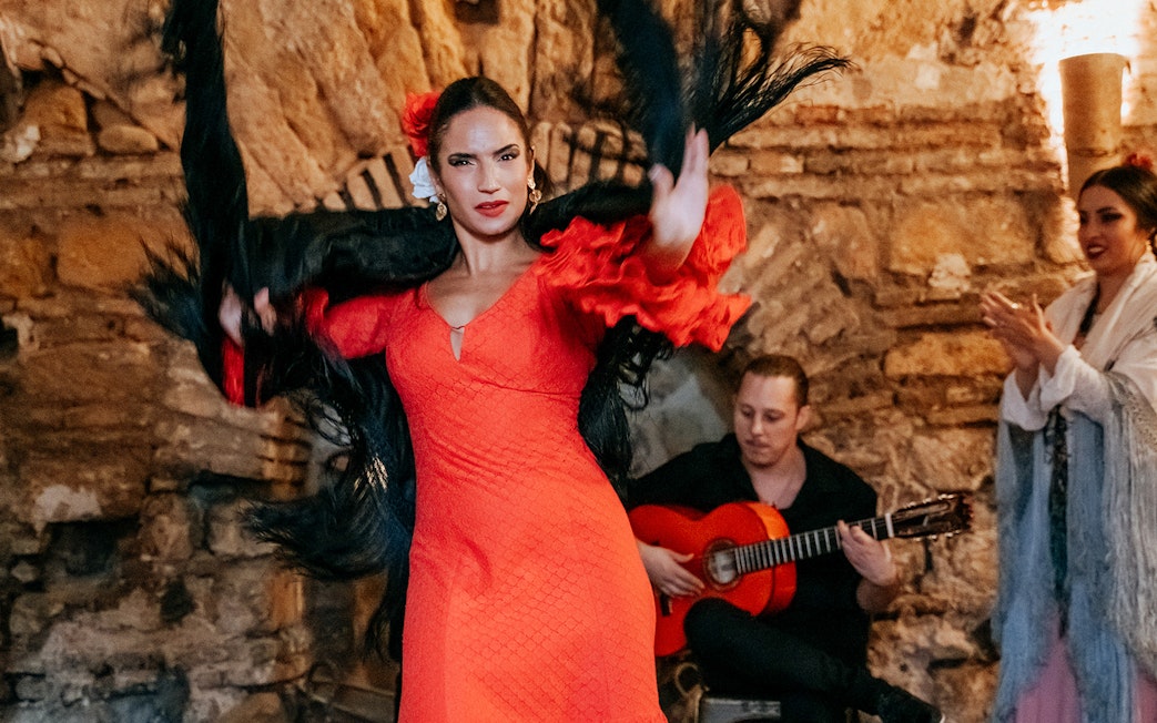 Flamenco dancer performing at Tablao en Baños Árabes de Santa María with guitarist in background.
