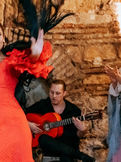 Flamenco dancer performing at Tablao en Baños Árabes de Santa María with guitarist in background.