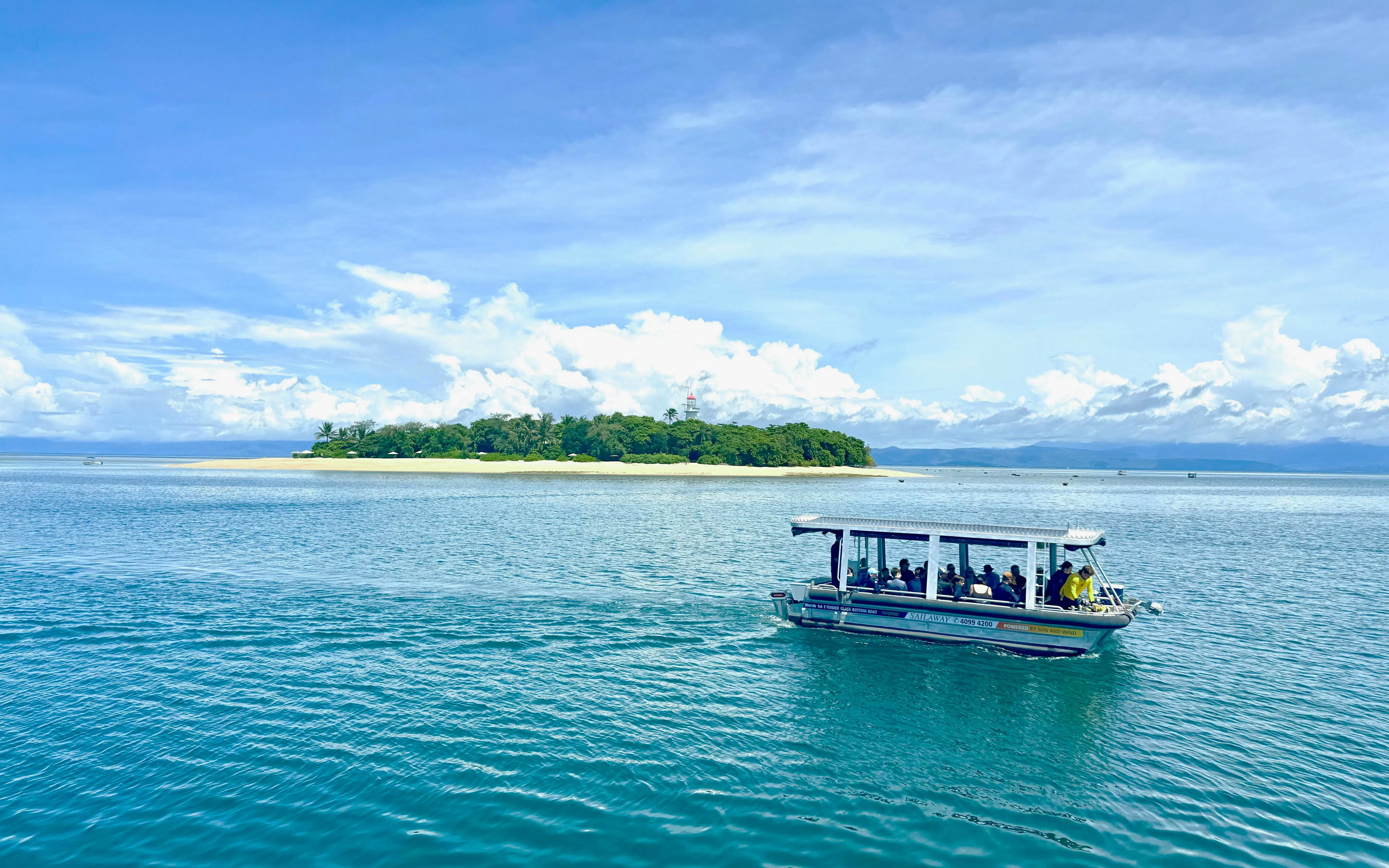 Glass-bottom boat near Mackay Coral Reef, Port Douglas, with island view in background.