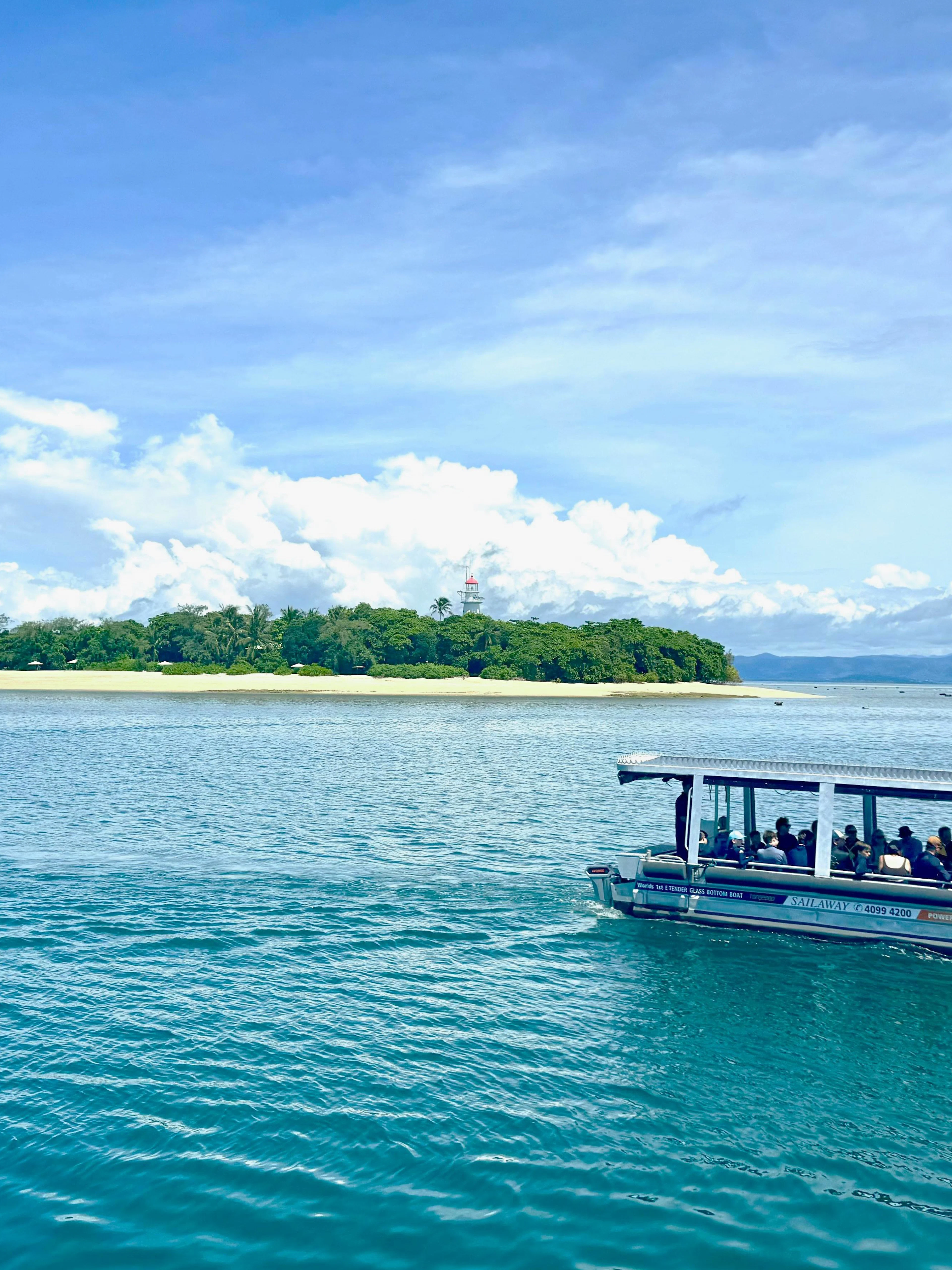 Glass-bottom boat near Mackay Coral Reef, Port Douglas, with island view in background.