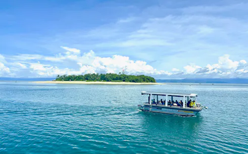 Glass-bottom boat near Mackay Coral Reef, Port Douglas, with island view in background.