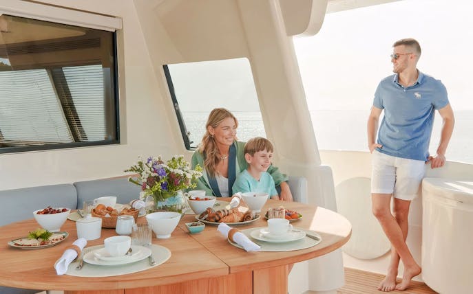Family enjoying meal on luxury yacht with ocean view.