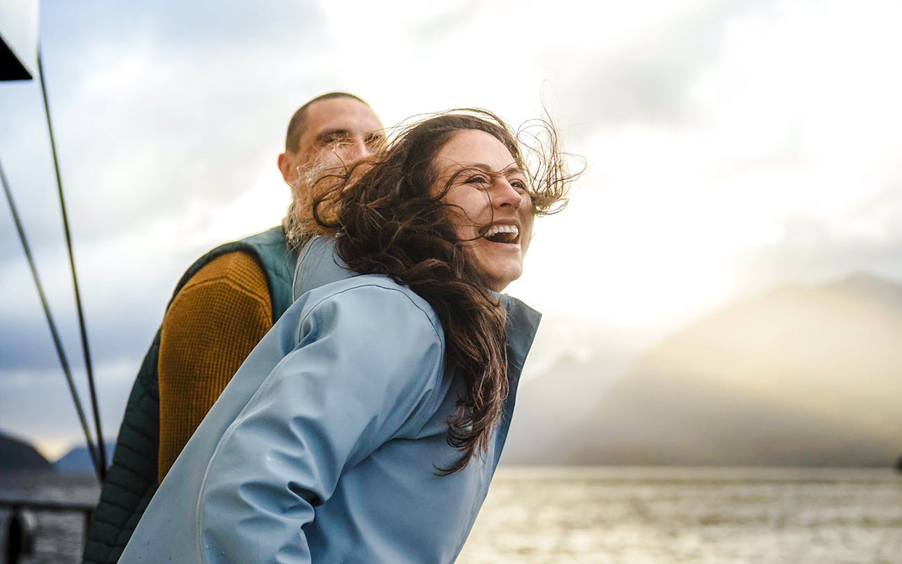 Couple enjoying a Doubtful Sound cruise with scenic mountain views.