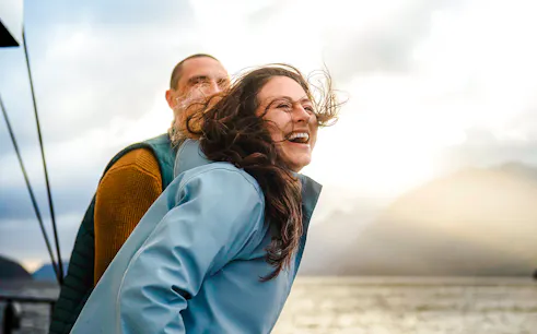 Couple enjoying a Doubtful Sound cruise with scenic mountain views.