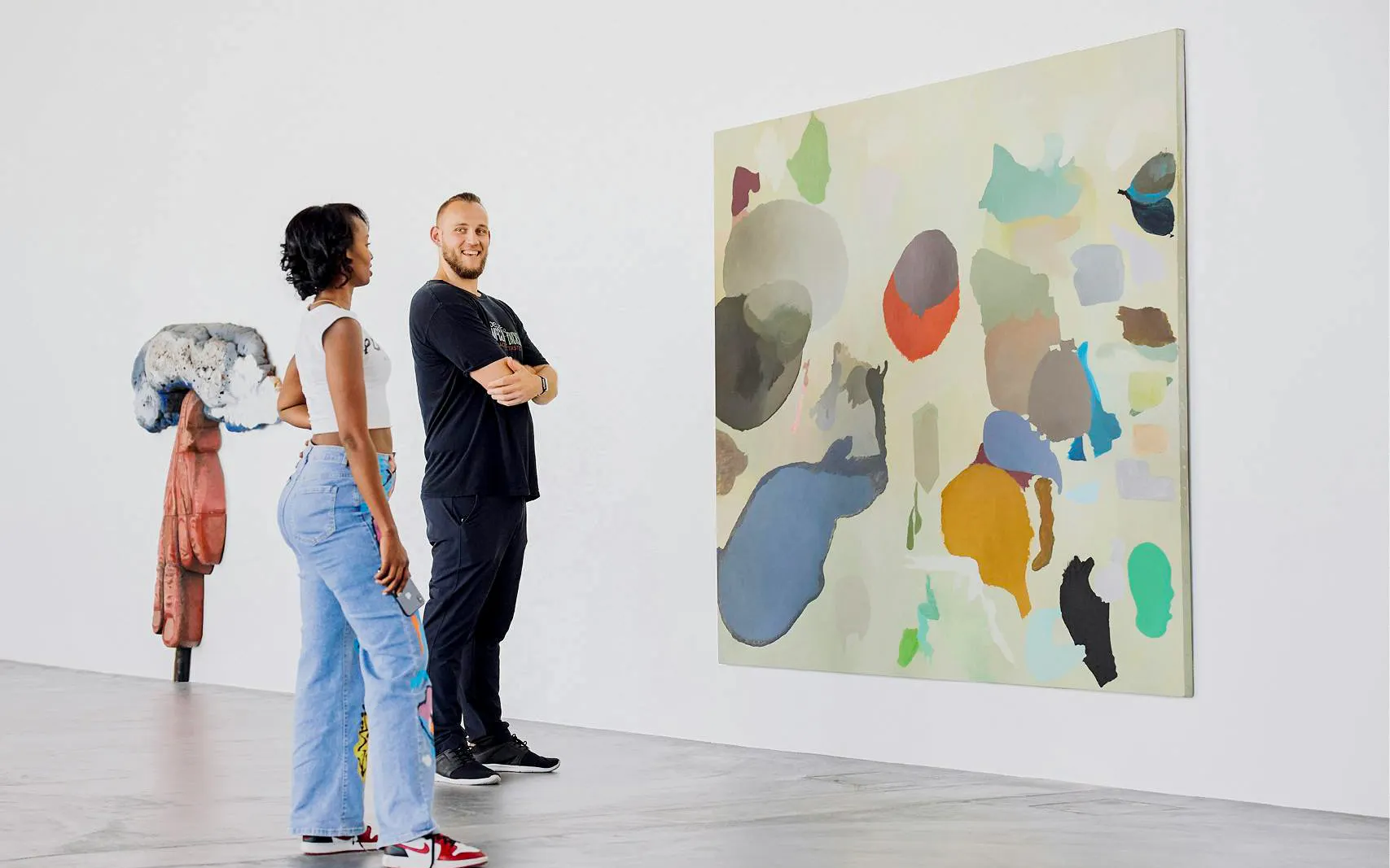 Couple admiring abstract painting in art museum gallery.