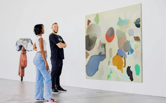 Couple admiring abstract painting in art museum gallery.