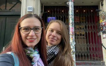 Two people in front of a graffiti-covered entrance in Berlin Kreuzberg.
