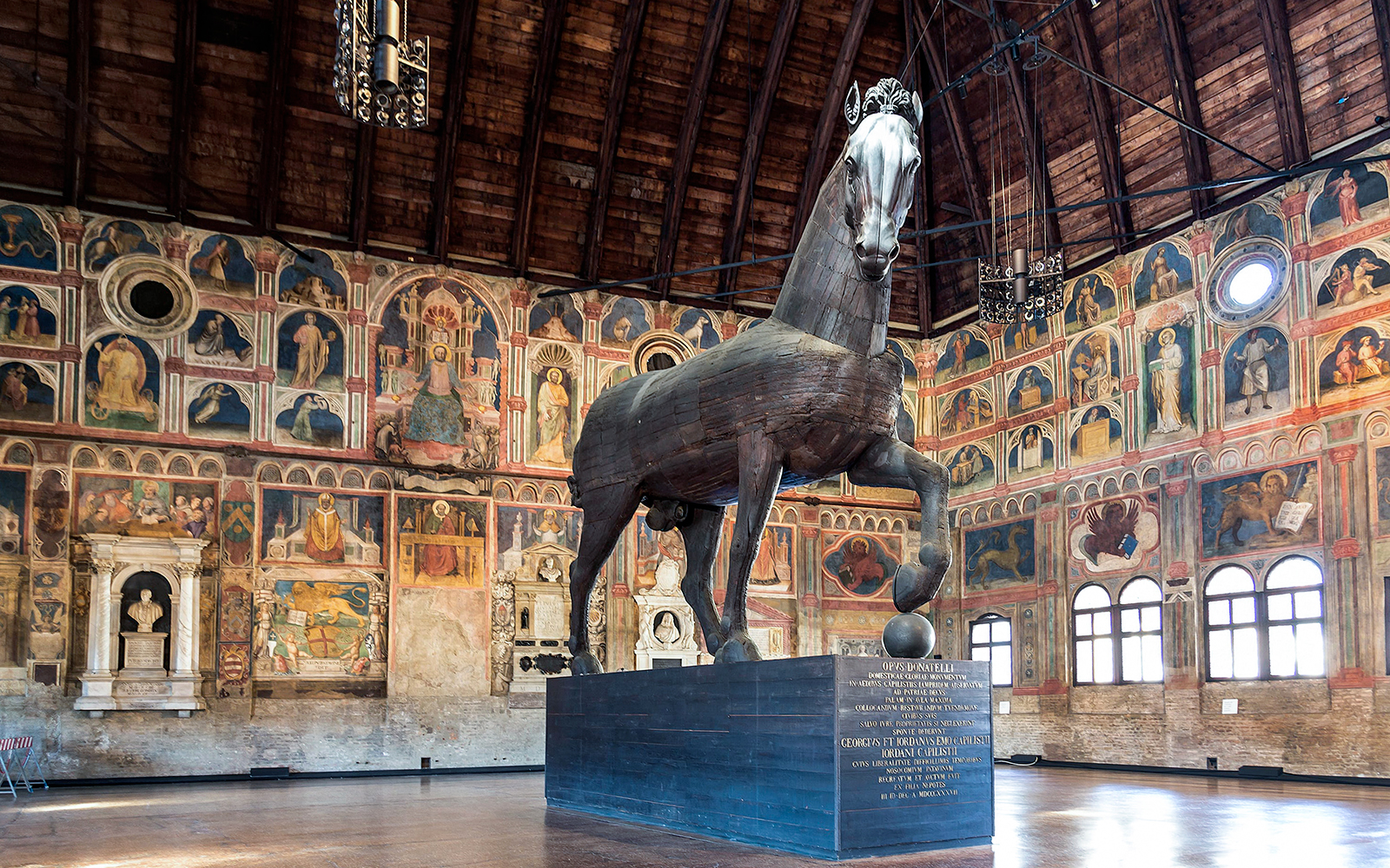 Equestrian statue inside Palazzo della Ragione, Padua, with frescoed walls, part of UNESCO Urbs Picta.