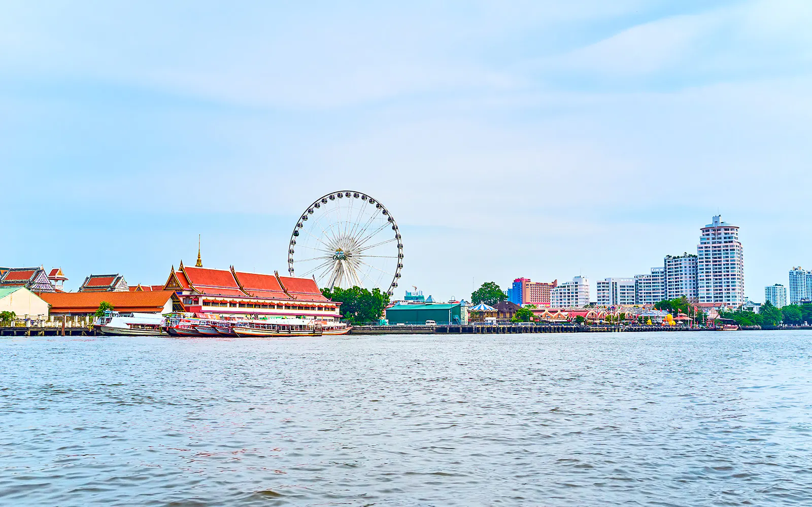 Asiatique Pier with ferris wheel and riverside buildings in Bangkok.