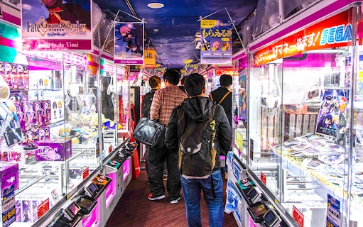 Visitors exploring arcade games in Akihabara during a retro gaming and anime walking tour.