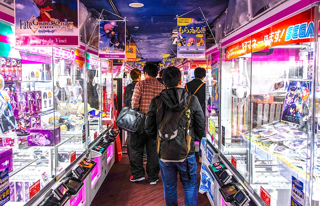 Visitors exploring arcade games in Akihabara during a retro gaming and anime walking tour.