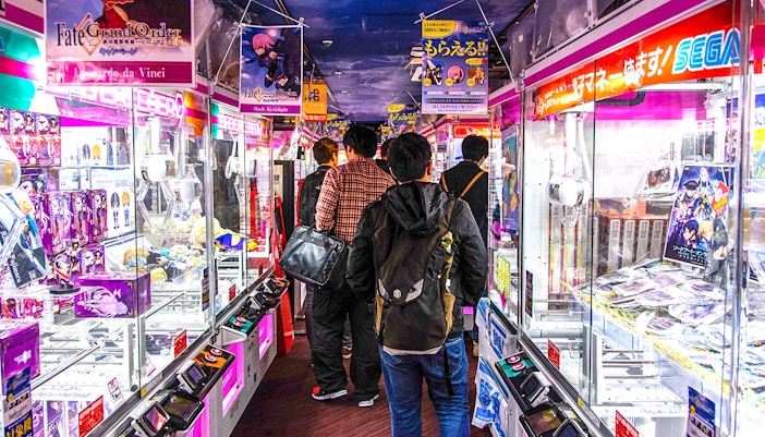 Visitors exploring arcade games in Akihabara during a retro gaming and anime walking tour.