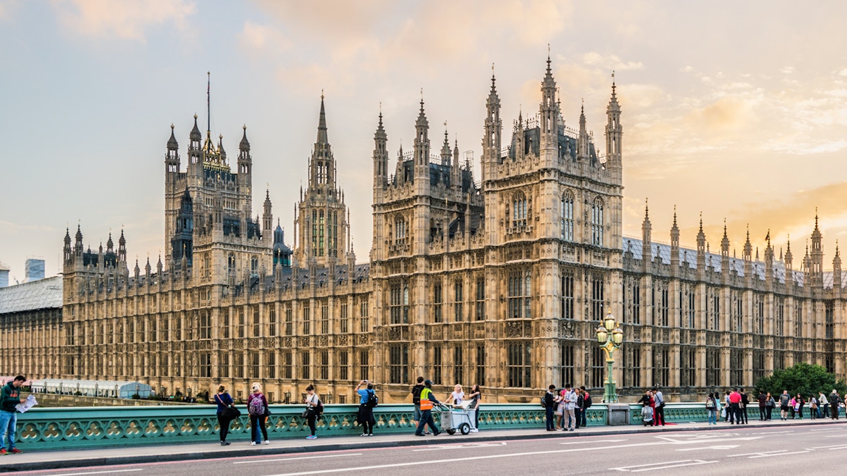 Palace of Westminster with Big Ben and tourists on Westminster Bridge, London.