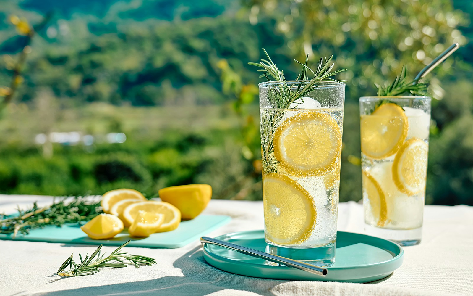 Refreshing summer drink with lemon and mint in a glass on a wooden table.