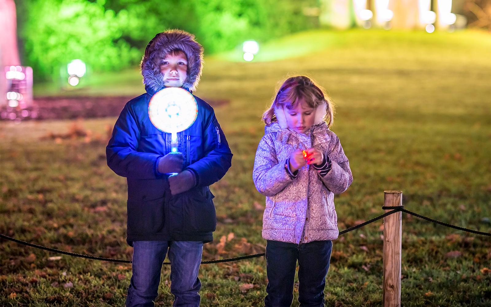 Children holding glowing lights at Christmas event in Kew Gardens.