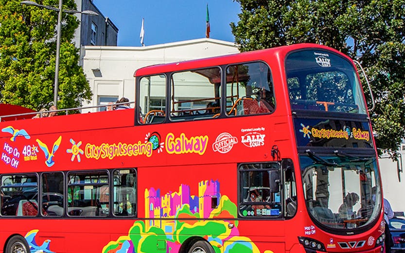 Red double-decker bus for City Sightseeing Galway tour on a sunny street.