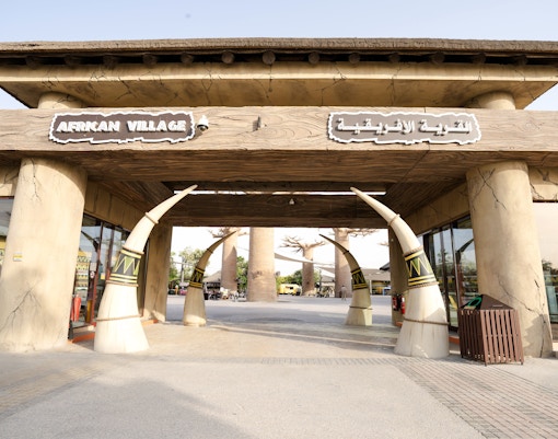 Entrance to African Village at Dubai Safari Park with tusk-shaped pillars.