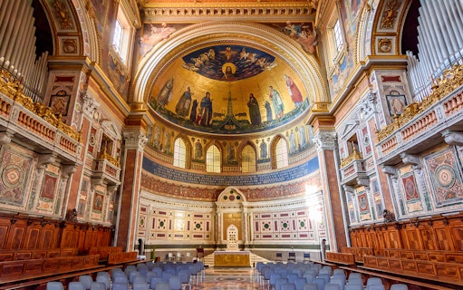 Interior of a Roman basilica with ornate frescoes and arches on the Appian Way tour.