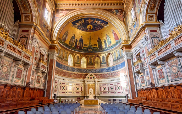 Interior of a Roman basilica with ornate frescoes and arches on the Appian Way tour.