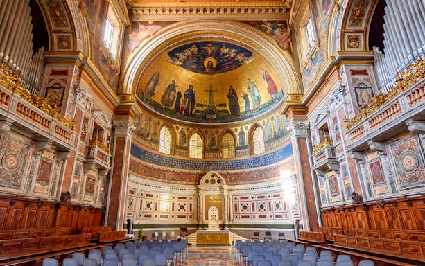 Interior of a Roman basilica with ornate frescoes and arches on the Appian Way tour.