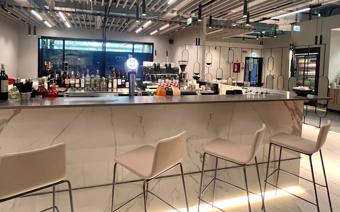 Bar area at Plaza Premium First Lounge, Rome Fiumicino Airport Terminal 1, with seating and drinks display.