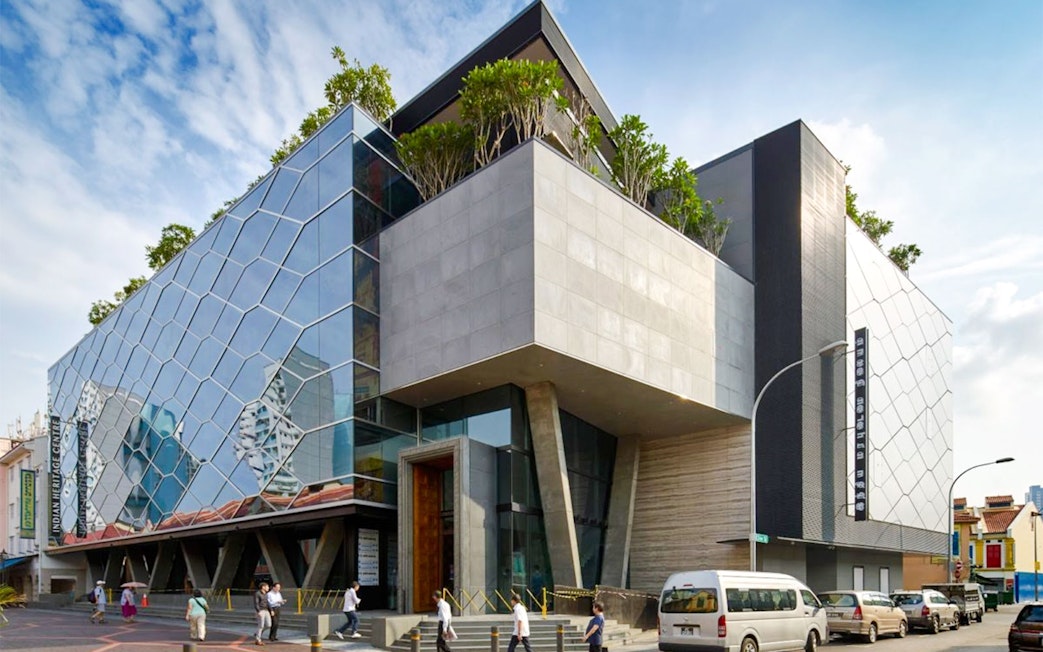 Modern glass and concrete facade of the Indian Heritage Centre in Singapore.
