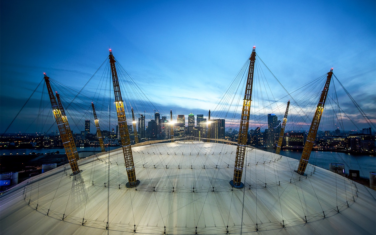 O2 Arena roof with city skyline at twilight, London.